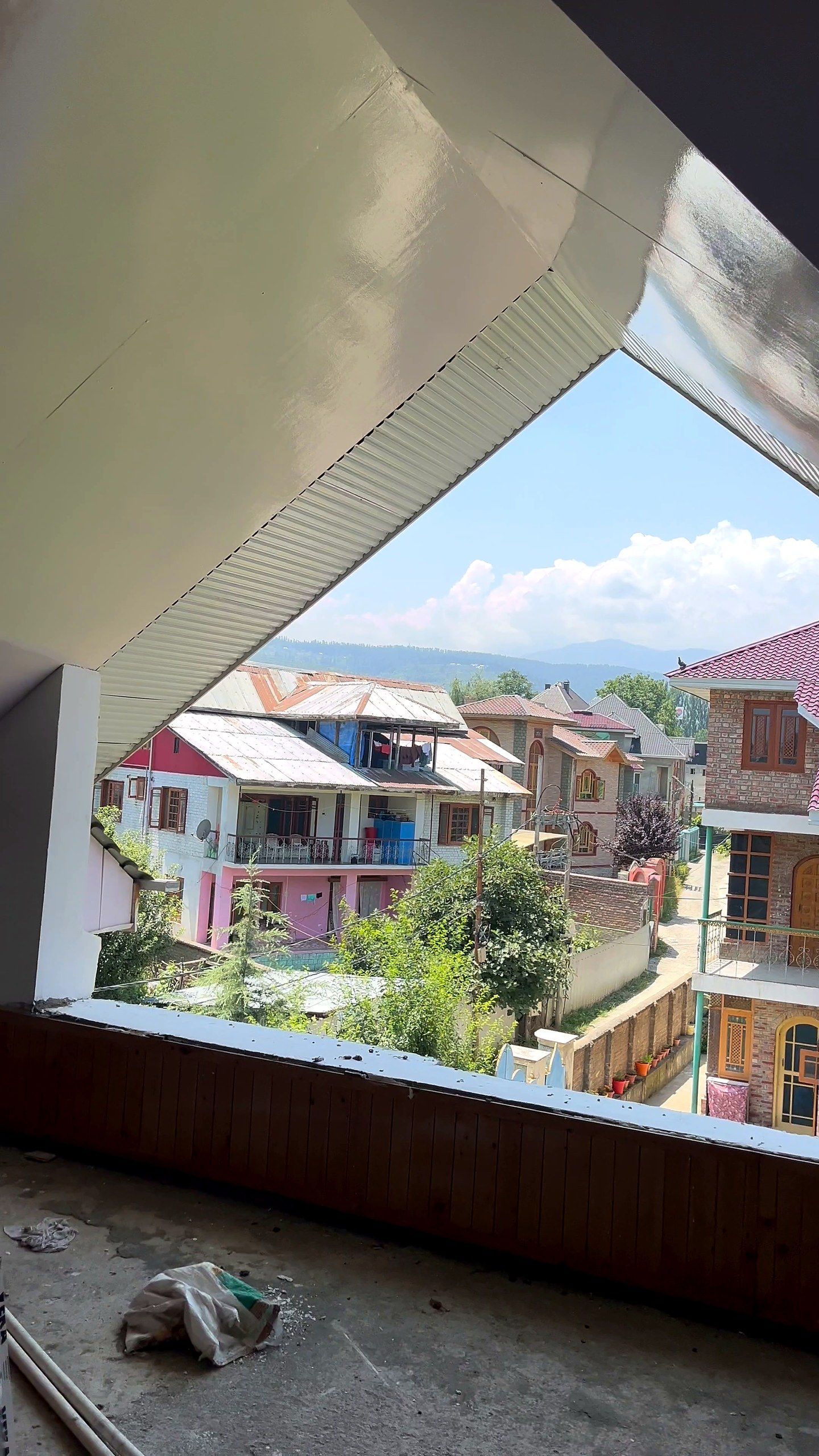 Triangular gable window framing Kashmiri rooftops and mountains