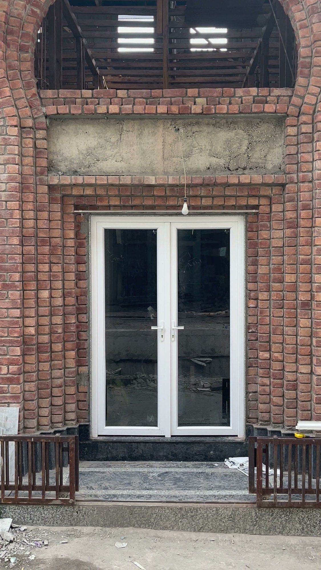 White uPVC French doors fitted by Standard Fabtech in an arched brick front