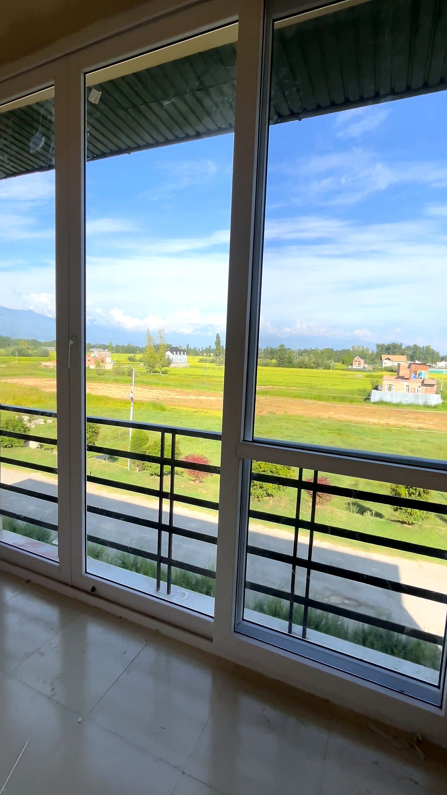 Corner of tall double-glazed windows looking over fields