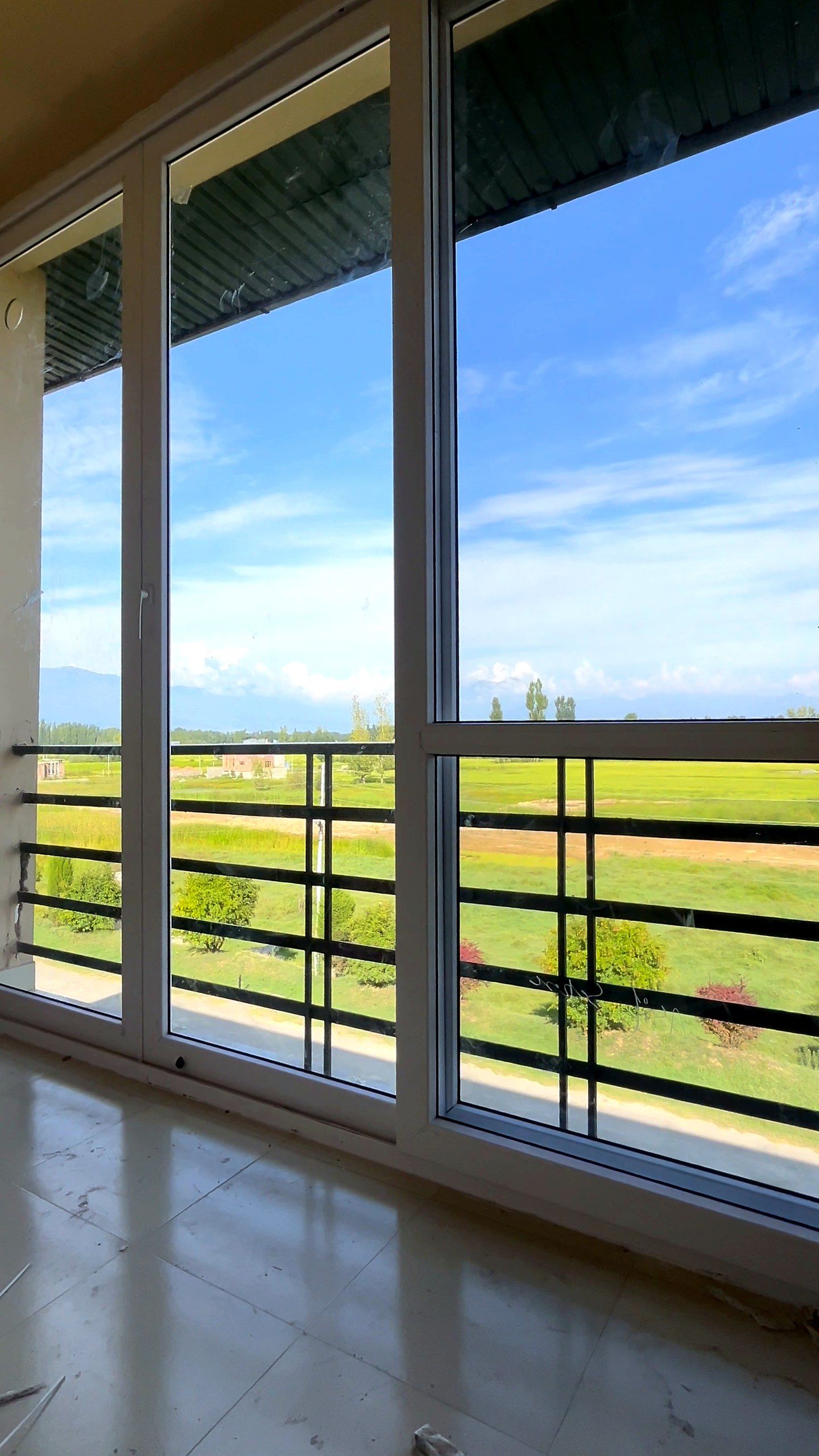 Three tall uPVC windows over a green landscape