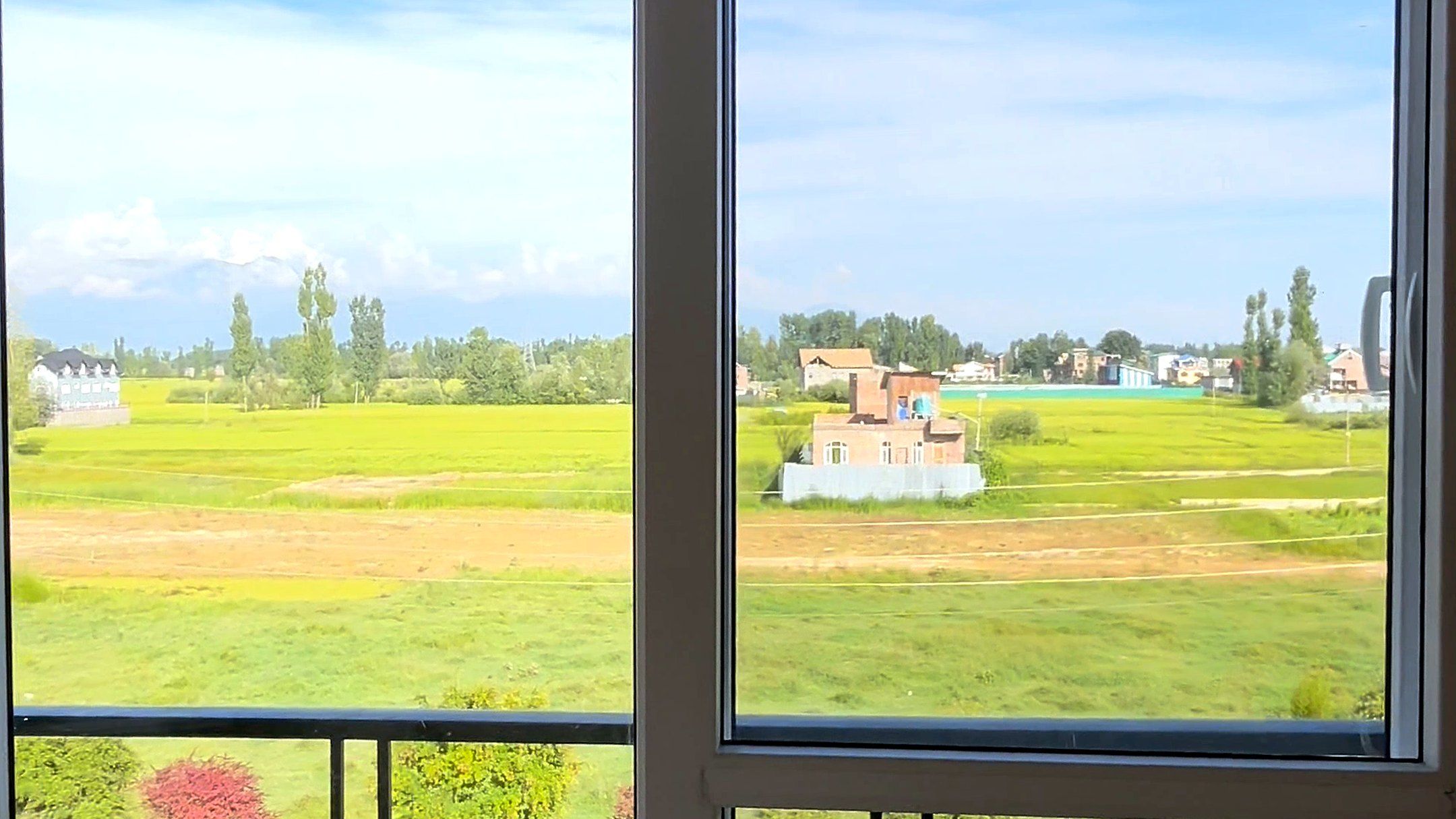 Full-height uPVC windows looking over green fields in Kashmir