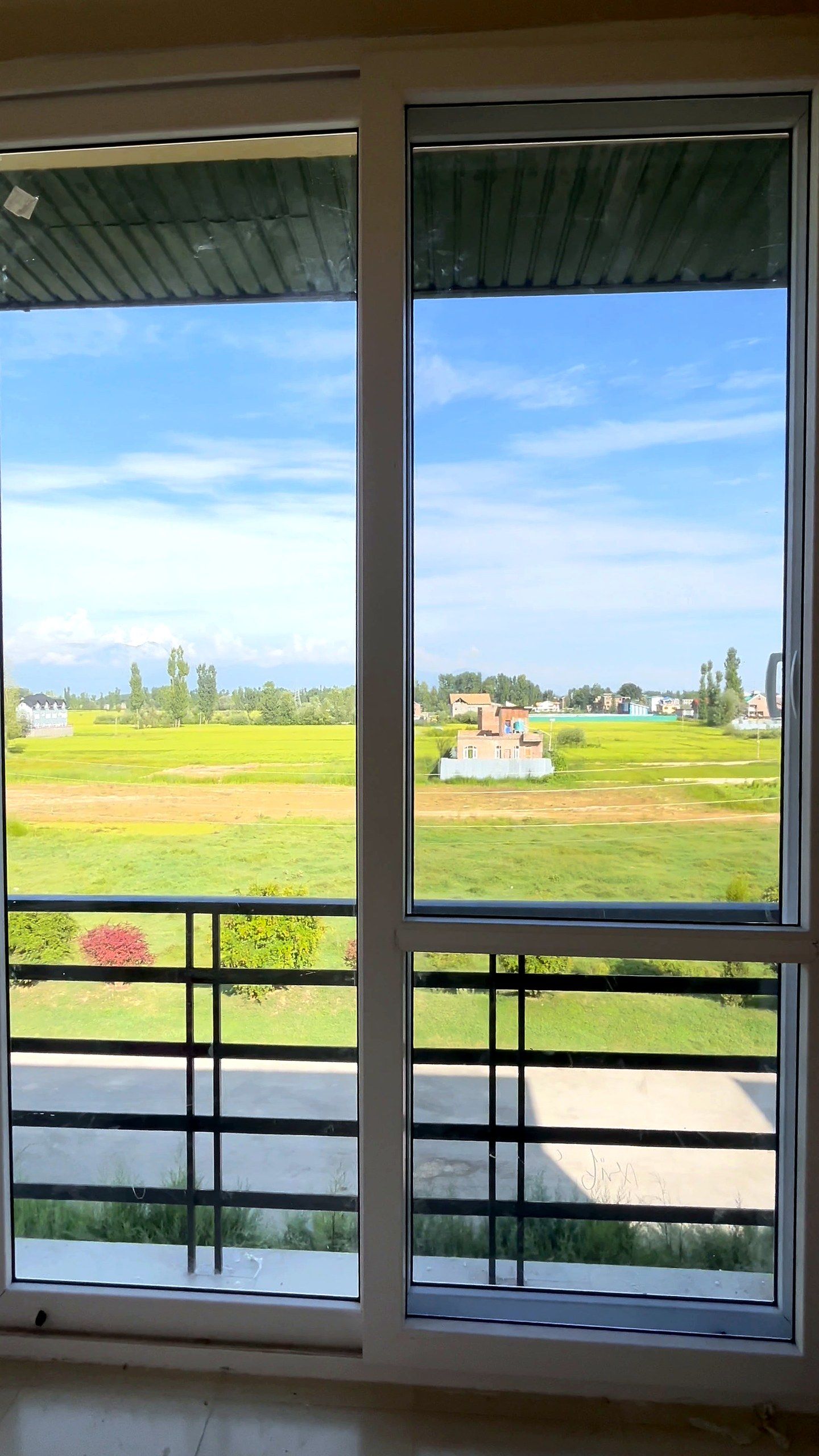 Full-height uPVC windows looking over green fields and distant mountains