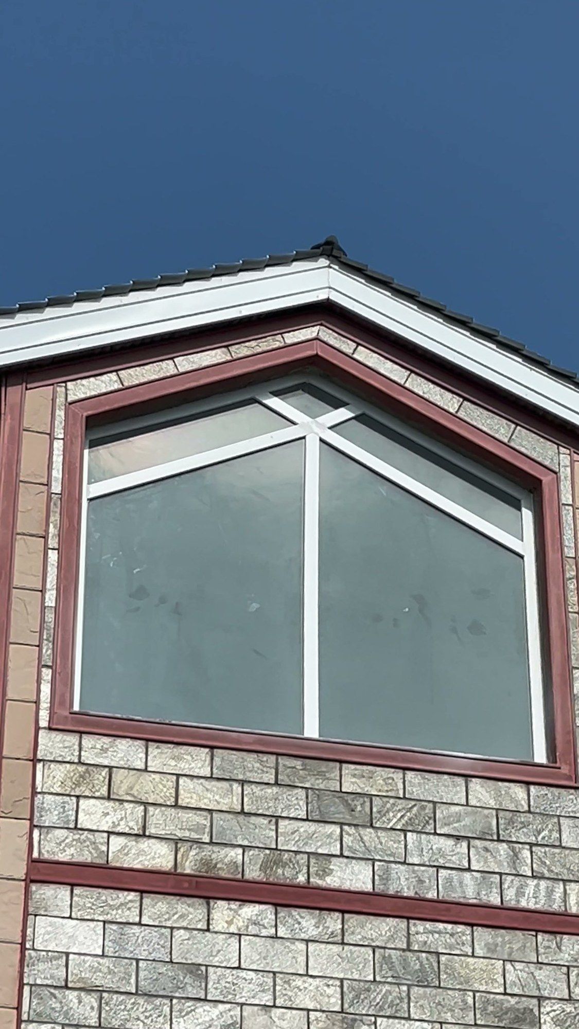 White uPVC casement and fixed window in the gable of a stone-clad house