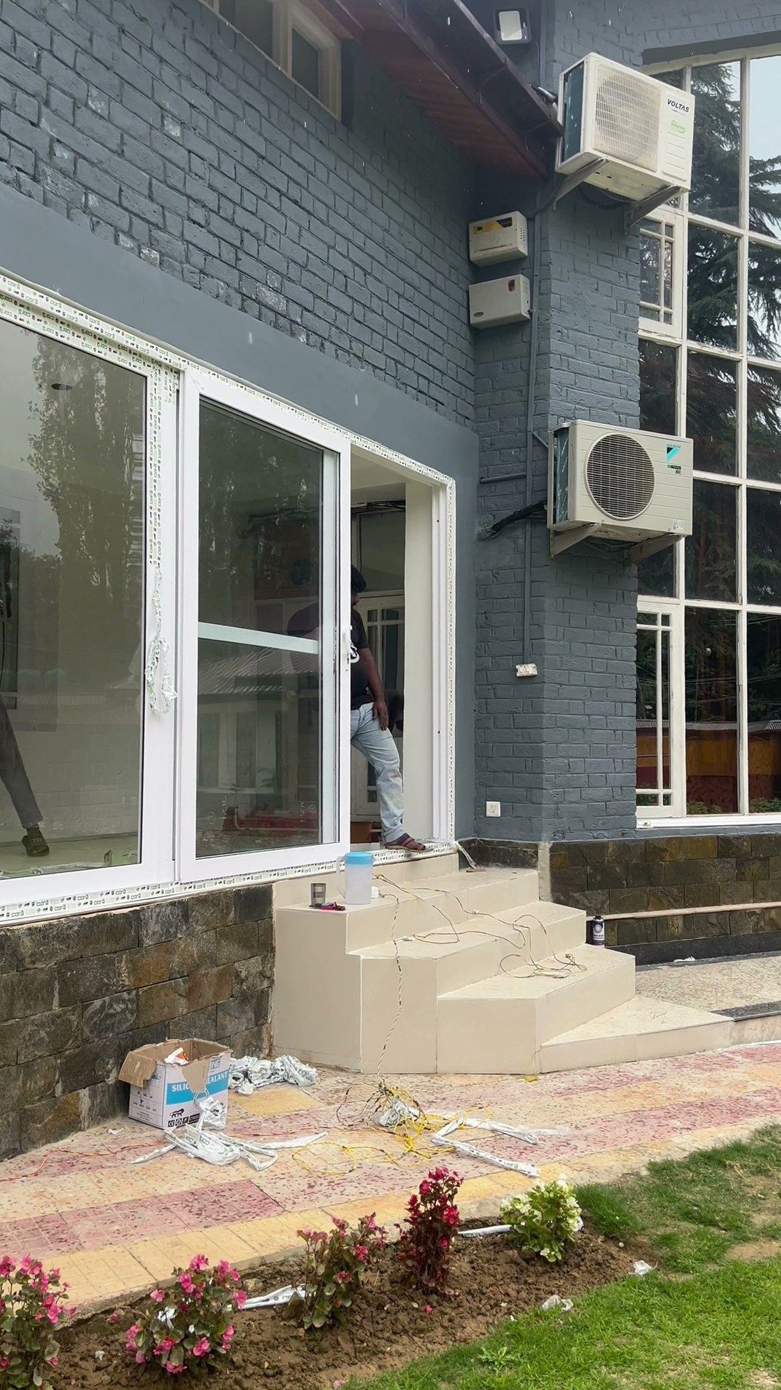 Grey house with a stone base and large white uPVC windows and doors
