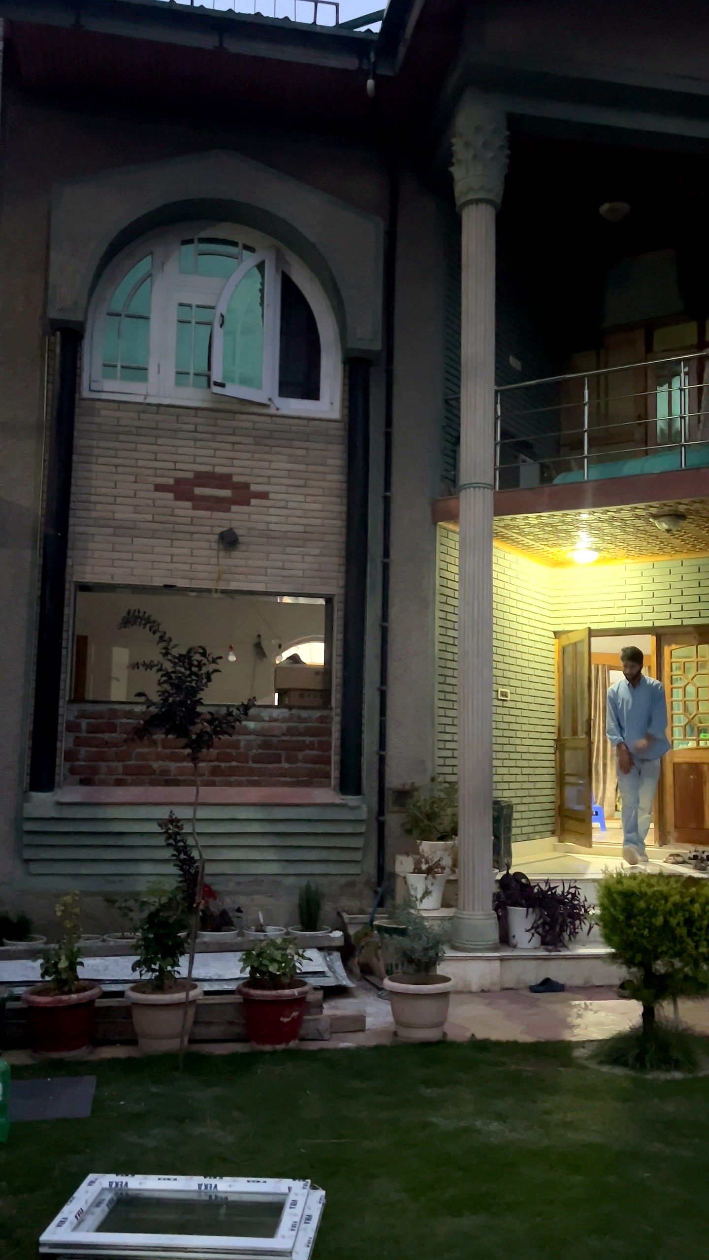Kashmir house at dusk with lights on behind new windows and doors
