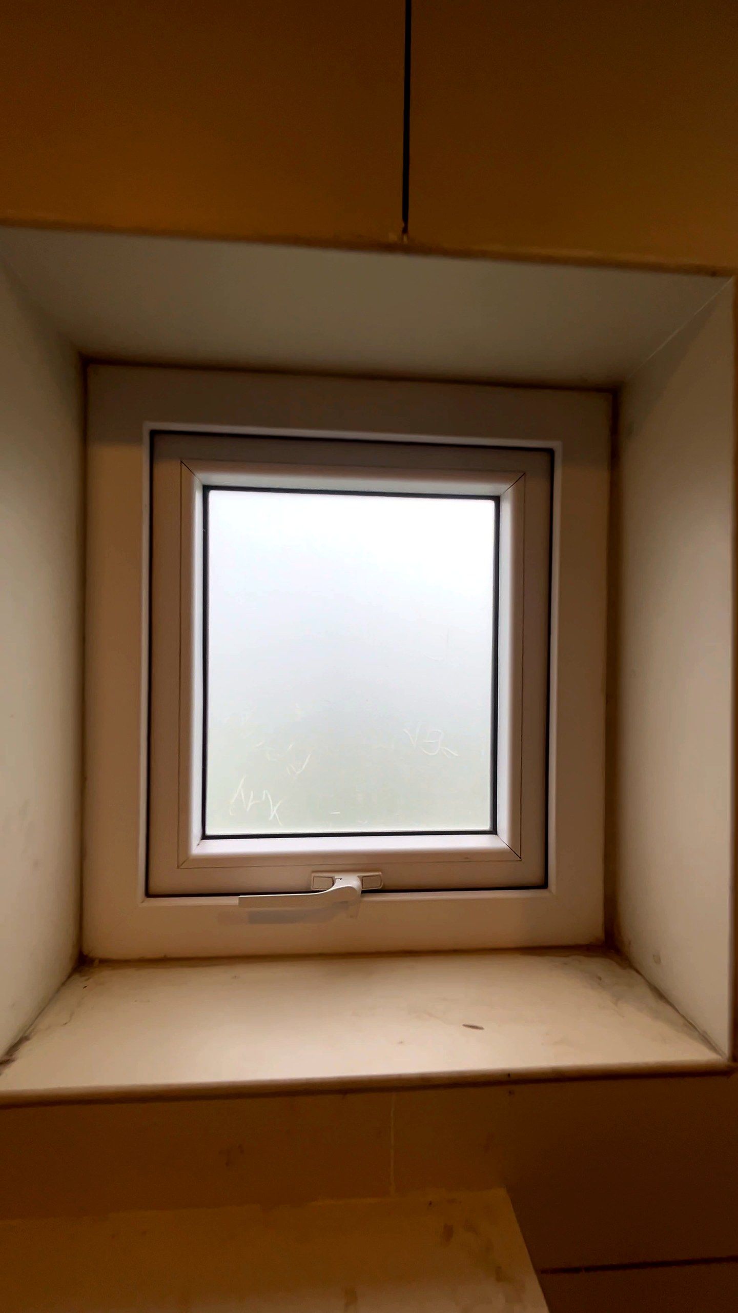 Top-hung uPVC window with frosted glass in a deep window reveal
