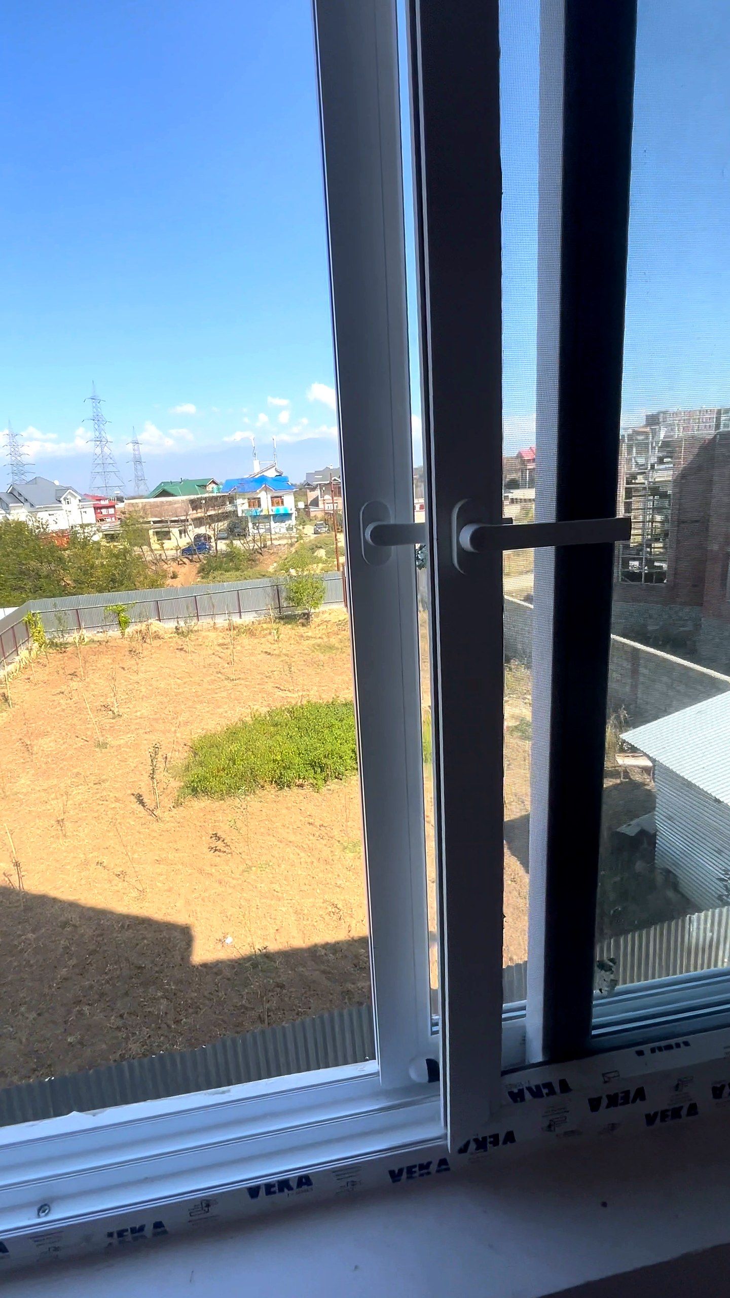 uPVC sliding window with an interlock and pull handle, looking over open ground